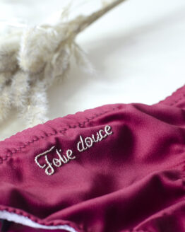 gros plan broderie folie douce maison finou Gros plan sur la broderie folie douce sur le devant d'une culotte bordeaux à plat