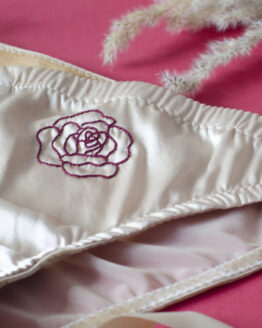 focus broderie rose maison finou Culotte à plat rose poudrée avec une broderie d'une rose bordeaux sur le devant au milieu