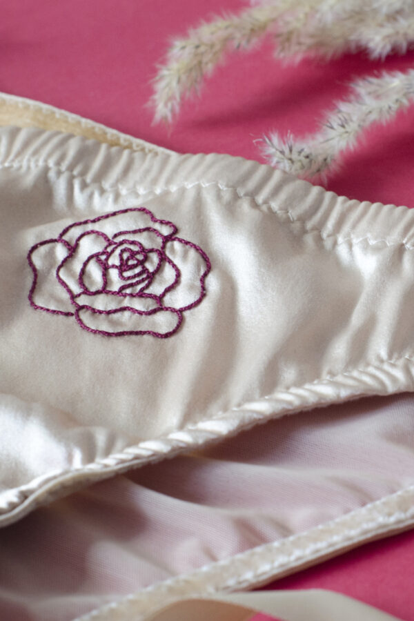 Culotte à plat rose poudrée avec une broderie d'une rose bordeaux sur le devant au milieu