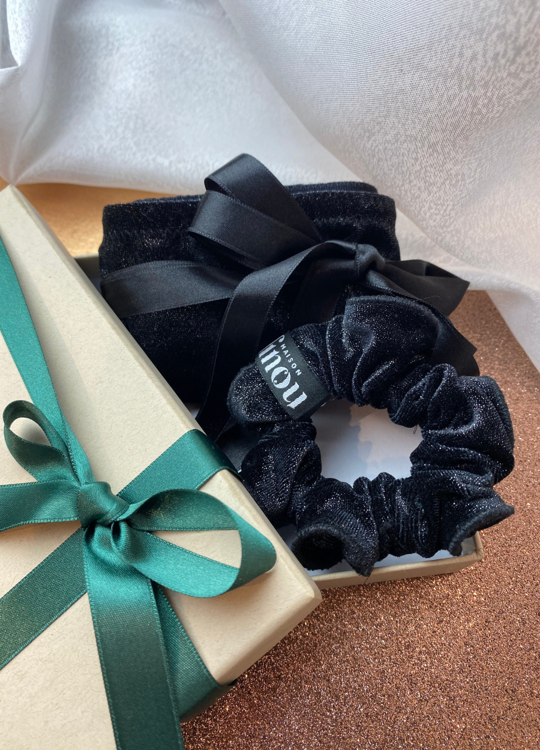 Coffret cadeau ouvert avec une culotte nouee en velours noir paillettes et son chouchou assortie, en velours noir paillettes egalement