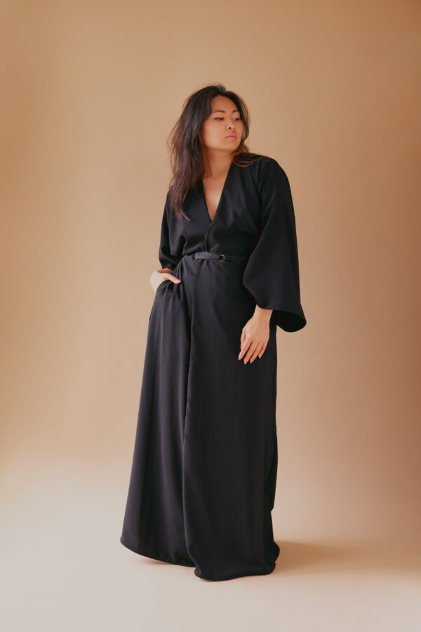 Femme debout portant une robe kimono longue manches longues noire, ceinturée à la taille