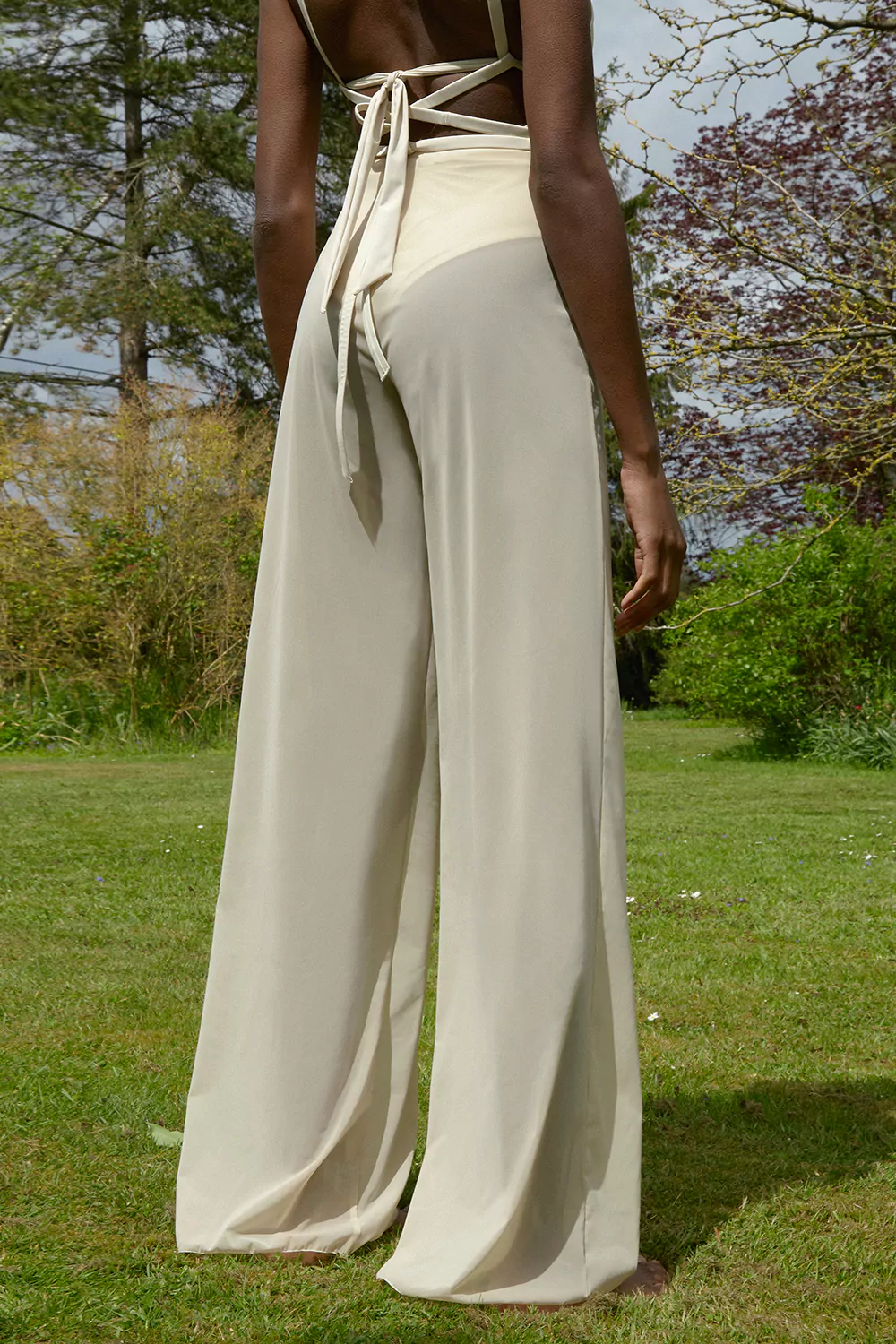 femme debout se tenant de dos et portant un pantalon de couleur écru