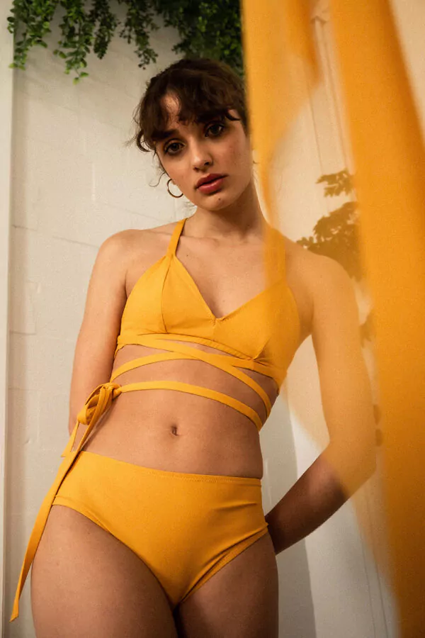 Femme debout portant un maillot de bain deux pièces jaune