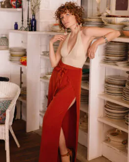 Femme portant un pantalon fendu terracotta en sortie de bain dans un restaurant en bordure de plage