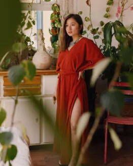 Femme portant une robe tunique terracotta fluide dans un restaurant de plage en sortie de bain