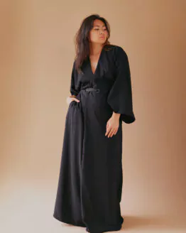 Femme debout portant une robe kimono longue manches longues noire, ceinturée à la taille