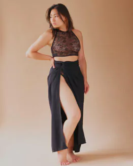 Femme debout portant un ensemble de lingerie en dentelle noire recouvert d'une jupe d'intérieure semblable à un paréo