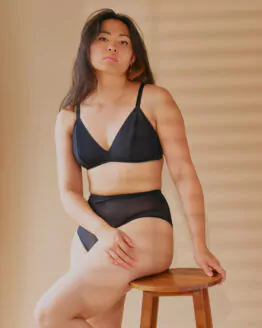 Femme assise sur un tabouret en bois portant un ensemble en tulle stretch noir