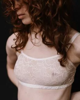 femme debout portant de la lingerie de mariage : une brassière en dentelle graphique blanche française ajustable au dos avec des réglettes